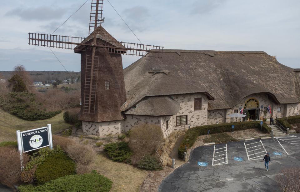 Gabriel Kroeze walks out into the parking lot on March 15 of the Tulp Outdoor Living store in Bourne to check on the blades of the familiar windmill, which are now turning again. The store opened March 1 at the base of the Sagamore Bridge.