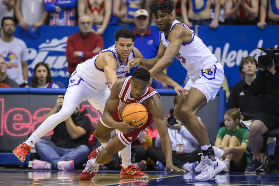 Indiana forward Jordan Geronimo (22) dives for a loose ball in front of Kansas guard Kevin McCullar Jr., left, and forward Zuby Ejiofor, right, during the first half of an NCAA college basketball game in Lawrence, Kan., Saturday, Dec. 17, 2022. (AP Photo/Reed Hoffmann)