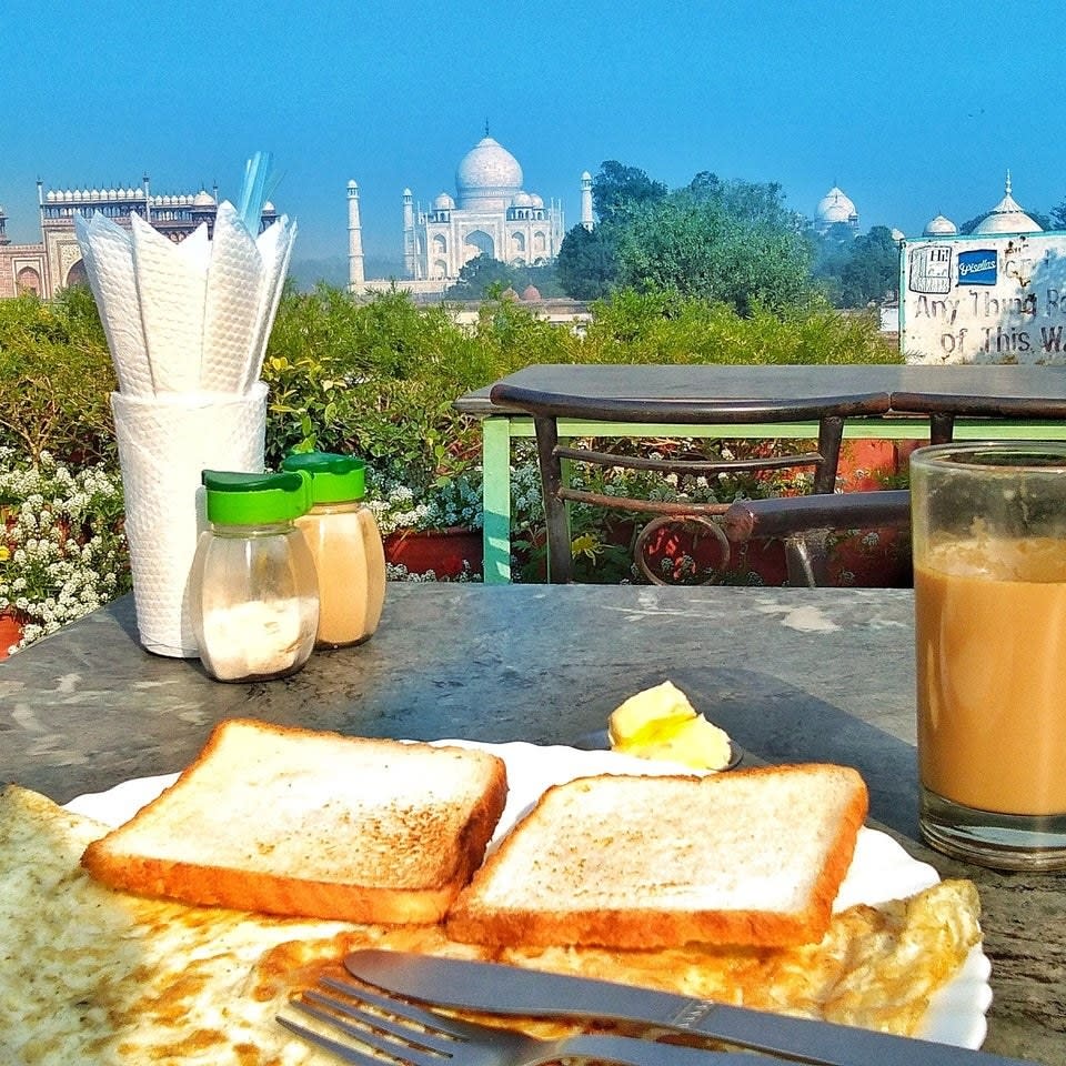 the Taj Mahal in the distance, with breakfast meal on a table in the foreground