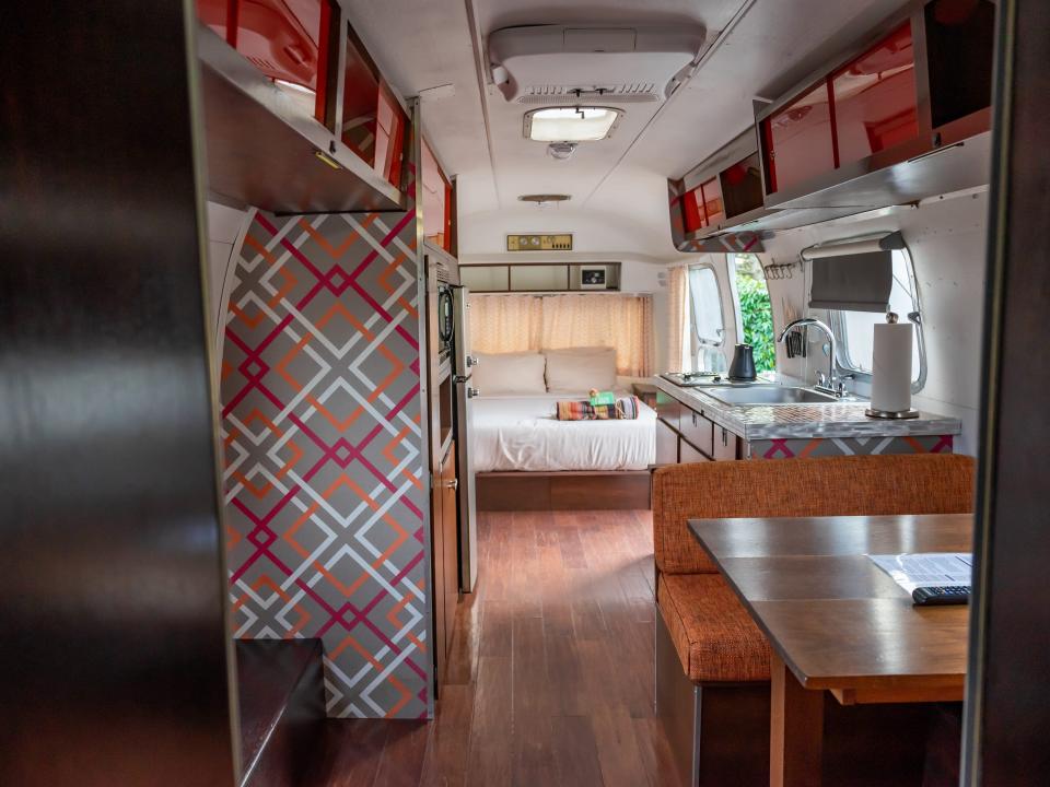 view of airstream interior with plaid wallpaper, bed, and small seating area