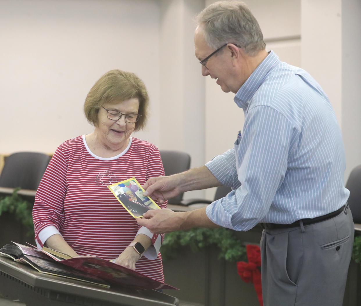 Former Macy's employee Joanna Bennett shows a photo from her retirement party to Stow Mayor John Pribonic Wednesday during a gathering in City Council chambers to talk about the defunct department store that anchored Stow-Kent Shopping Center.