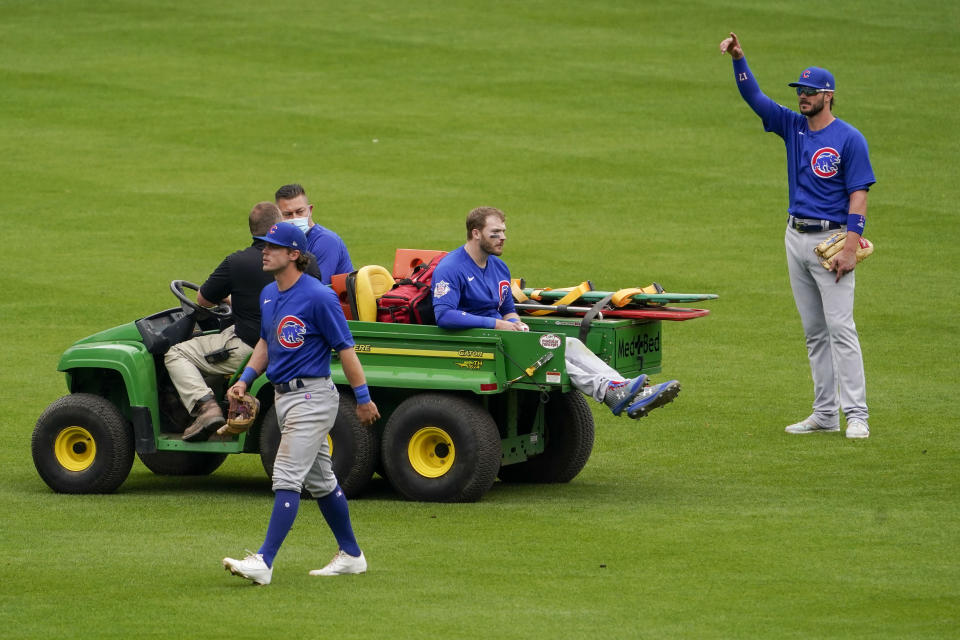 Chicago Cubs center fielder Ian Happ, center, is carted off after a collision with teammate Nico Hoerner, foreground, in the eighth inning during a baseball game against the Cincinnati Reds in Cincinnati on Sunday, May 2, 2021. (AP Photo/Jeff Dean)