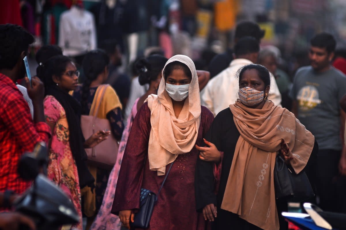 Women wear masks as they pass through a crowded street, amidst the spike in Covid-19 cases (EPA)