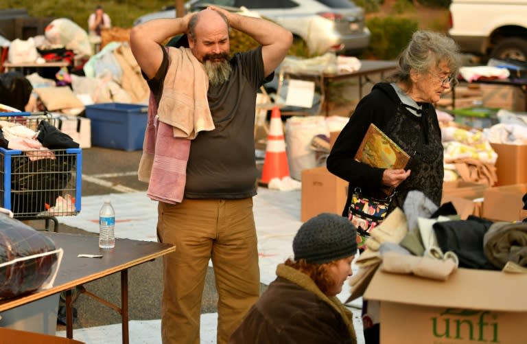 Rob Lowe (L) sighs while searching through donated clothing at an encampment for fire evacuees at a Walmart parking lot in Chico, California