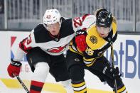 New Jersey Devils' Mikhail Maltsev (23) and Boston Bruins' Connor Clifton (75) battle for the puck during the first period of an NHL hockey game, Sunday, March 7, 2021, in Boston. (AP Photo/Michael Dwyer)