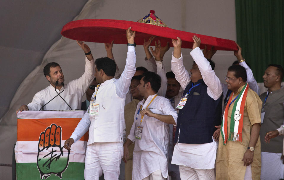 FILE - In this Tuesday, Feb. 26, 2019 file photo, Congress party members hold a giant traditional Assamese hat called a Japi to present to party President Rahul Gandhi, left, during a public rally in Gauhati, India. The final phase of India’s marathon general election will be held on Sunday, May 19. The first of the election’s seven staggered phases was held on April 11. Vote counting is scheduled to start on May 23. India has 900 million eligible voters. (AP Photo/Anupam Nath, File)