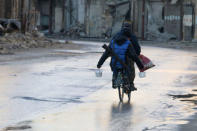 A rebel fighter carries food while riding a bicycle and carrying his weapon on his back in rebel-held besieged old Aleppo, Syria December 2, 2016. REUTERS/Abdalrhman Ismail
