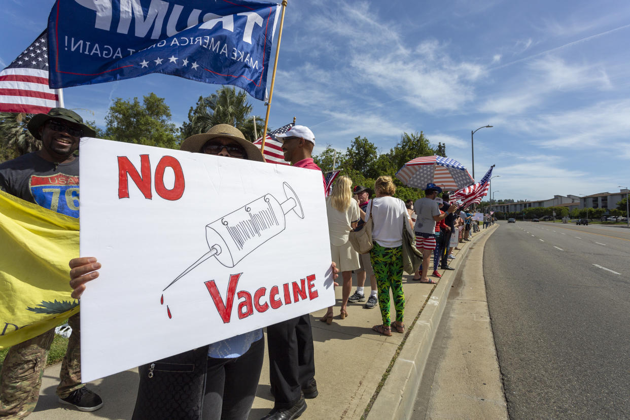 A protester holds an anti-vaccination sign as supporters of President Donald Trump rally to reopen California as the coronavirus pandemic continues to worsen, on May 16, 2020 in Woodland Hills, California. (David McNew/Getty Images)