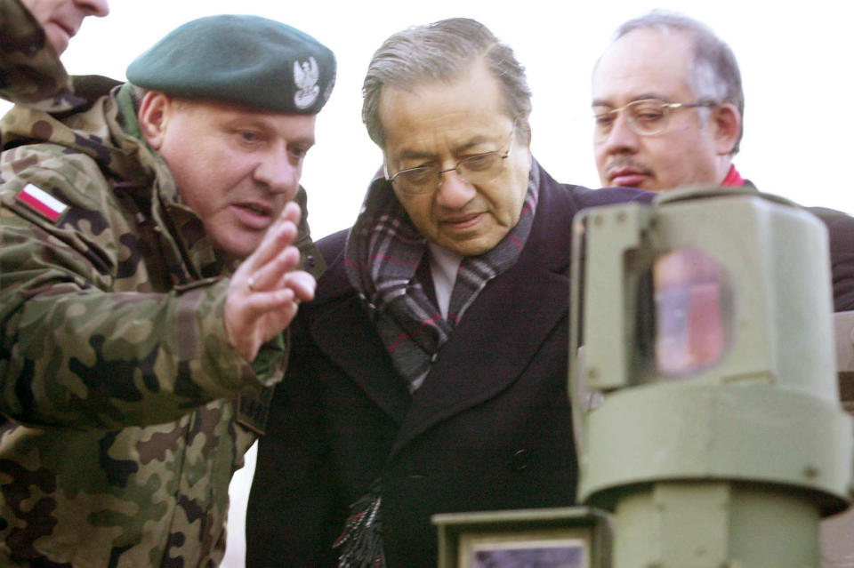 FILE - A Polish military officer, left, shows a T-91 tank to Malaysia's Prime Minister Mahathir Mohamad, center, with his Defence Minister Najib Razak, right, during a show in Wesola military camp, near Warsaw, March 21, 2002. Najib Razak on Tuesday, Aug. 23, 2022 was Malaysia’s first former prime minister to go to prison -- a mighty fall for a veteran British-educated politician whose father and uncle were the country’s second and third prime ministers, respectively. The 1MDB financial scandal that brought him down was not just a personal blow but shook the stranglehold his United Malays National Organization party had over Malaysian politics. (AP Photo/Czarek Sokolowski, file)