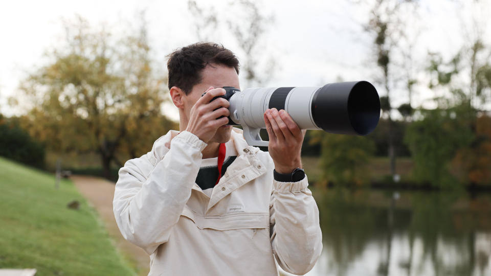 Canon RF 200-800mm f/6.3-9 IS USM lens on a Canon EOS R5 camera held up to man's face