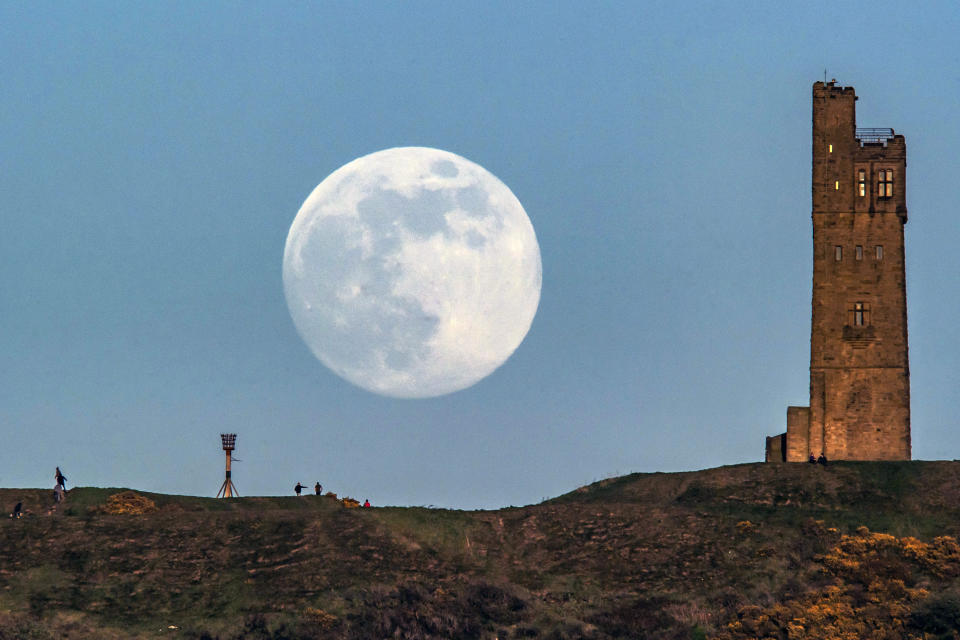 The moon rises behind Victoria Tower on Castle Hill in Huddersfield.