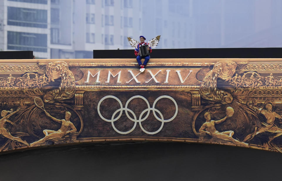 An artist sits on a bridge in Paris, France, during the opening ceremony of the 2024 Summer Olympics, Friday, July 26, 2024. / Credit: Kirsty Wigglesworth / AP