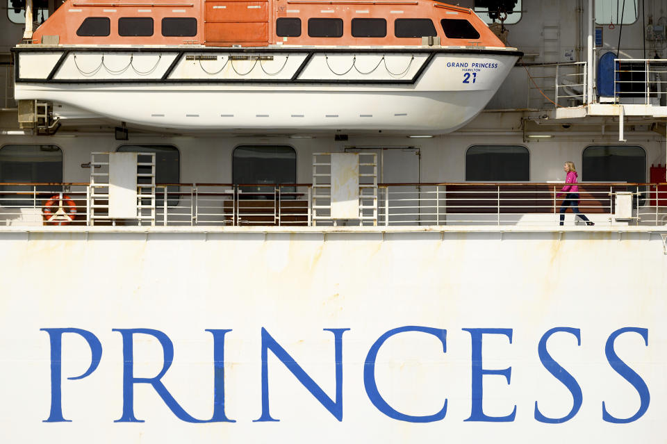 A passenger walks along a deck aboard the Grand Princess as it maintains a holding pattern about 25 miles off the coast of San Francisco on Sunday, March 8, 2020. The ship is expected to dock in Oakland in the east San Francisco Bay on Monday. California Gov. Gavin Newsom and the mayor of Oakland sought Sunday to reassure the public that none of the passengers from the ship with multiple cases of the new coronavirus will be released into the public before undergoing a 14-day quarantine. (AP Photo/Noah Berger)