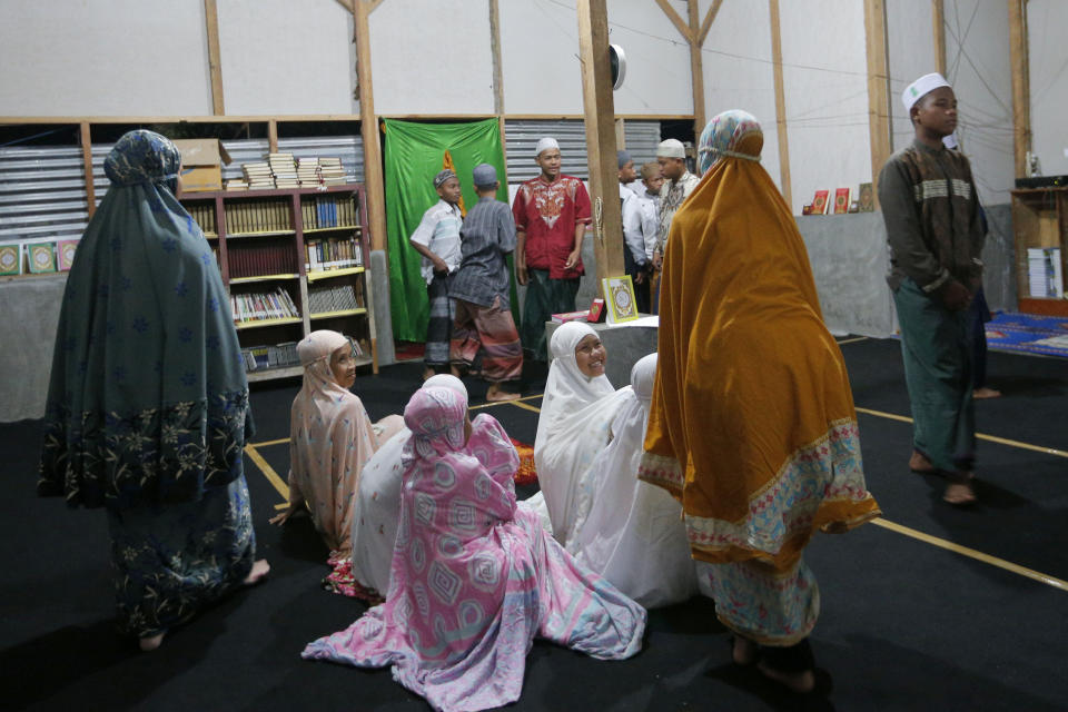 In this April 2, 2019, photo, children who survived the Sept. 28, 2018, earthquake and tsunami in Palu, Indonesia, prepare to pray at an Islamic boarding school built by the Islamic Defenders Front. The organization is better known for vigilante actions against gays, Christmas decorations and prostitution, but over the past decade and a half it has repurposed its militia into a force that's as adept at searching for victims buried under earthquake rubble and distributing aid as it is at inspiring fear. (AP Photo/Tatan Syuflana)