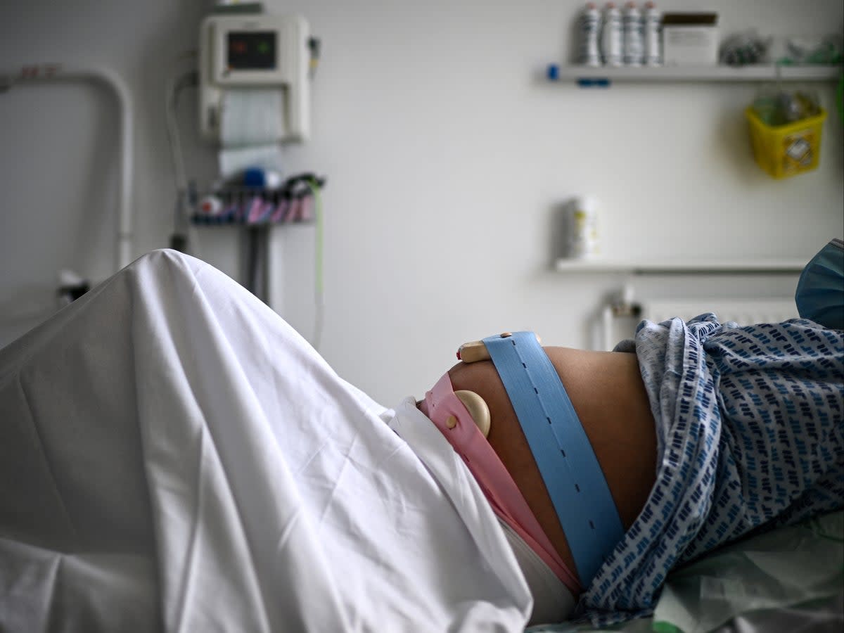 A pregnant woman lies on her bed with monitoring devices placed on her belly as she gets ready before delivering her child at the maternity ward of a hospital in Paris on June 29, 2022 (Christophe Archambault/AFP via Getty Images)