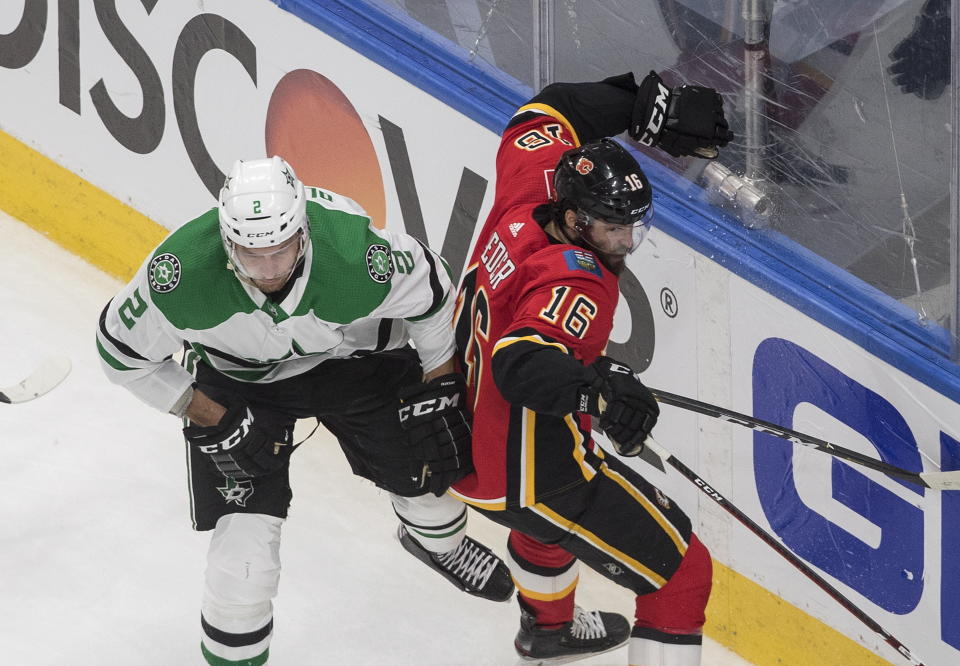 Calgary Flames' Tobias Rieder (16) is checked by Dallas Stars' Jamie Oleksiak (2) during the second period in the first round NHL Stanley Cup playoff hockey series, Friday, Aug. 14, 2020, in Edmonton, Alberta. (Jason Franson/The Canadian Press via AP)