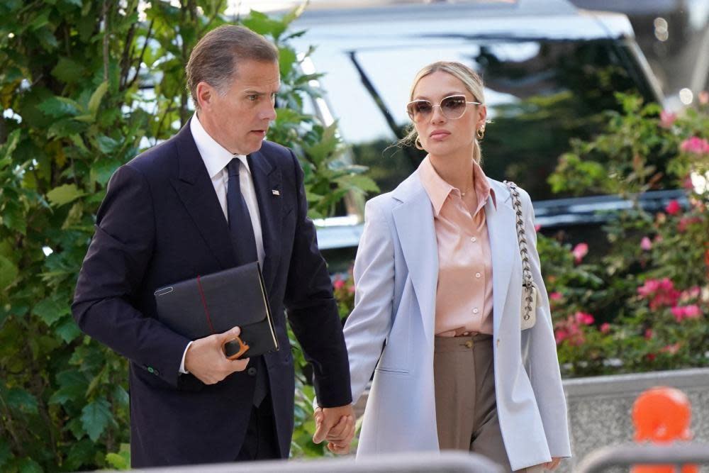 Hunter Biden in a navy suit and his wife Melissa Cohen, wearing a white coat, walk into court holding hands 