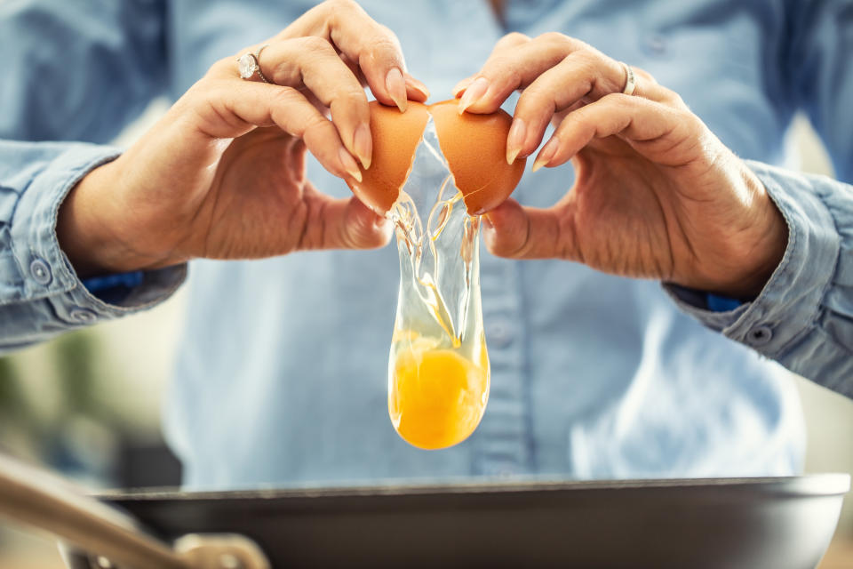 Someone cracking eggs into a skillet.