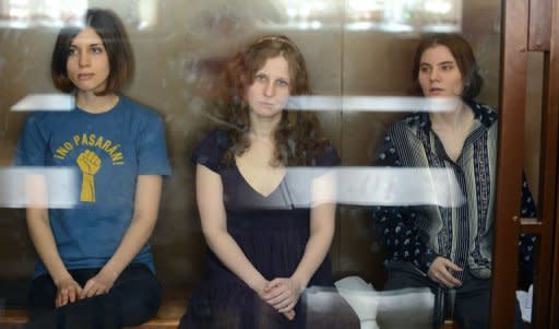 The three members of the Russian punk band "Pussy Riot" -- Nadezhda Tolokonnikova (left), Maria Alyokhina (centre) and Yekaterina Samutsevich -- sit inside a glass enclosure during a court hearing in Moscow