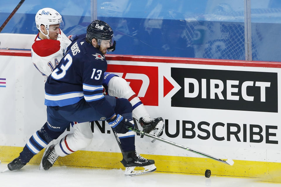 Winnipeg Jets' Pierre-Luc Dubois (13) and Montreal Canadiens' Nick Suzuki (14) compete for the puck during the first period of an NHL hockey game Saturday, Feb. 27, 2021, in Winnipeg, Manitoba. (John Woods/The Canadian Press via AP)