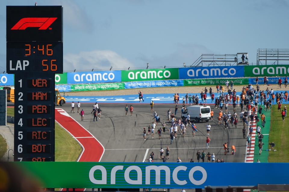 F1 fans race down the hill from turn 1 to get a closer look at the drivers and watch the trophy presentations following the Aramco U.S. Grand Prix at Circuit of the Americas on October 24, 2021 in Austin, TX