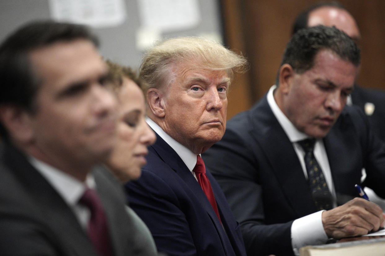 Former President Donald Trump appears in court, looking resigned, with members of his legal team.