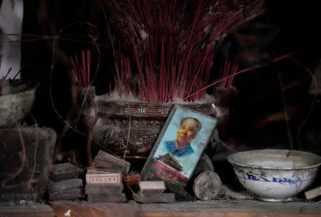 A card featuring the late Chinese Chairman Mao Zedong and Tiananmen Gate is seen next to a shrine in the old dwelling of surviving villager Wang Guocheng, at a minority village destroyed in the 2008 Sichuan earthquake in Wenchuan county, Sichuan province, China, April 5, 2018. REUTERS/Jason Lee