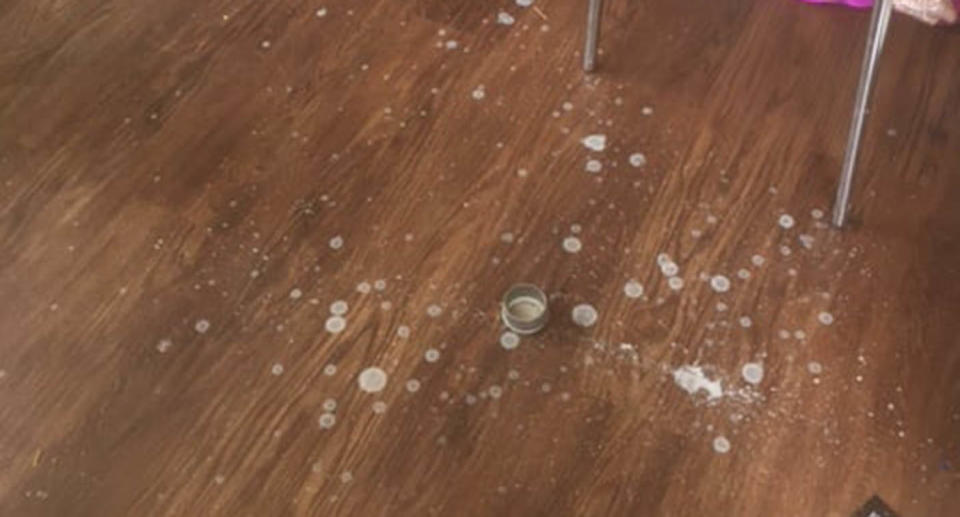 A Kmart shopper's photo of her wooden floor with a small tin and candle wax stains surrounding it.