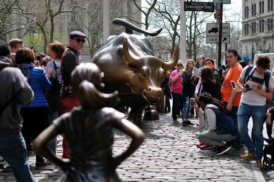 The ‘Fearless Girl’ (L) statue stands facing the ‘Charging Bull’ as tourists take pictures in New York on April 12, 2017. Photo: JEWEL SAMAD/AFP/Getty Images