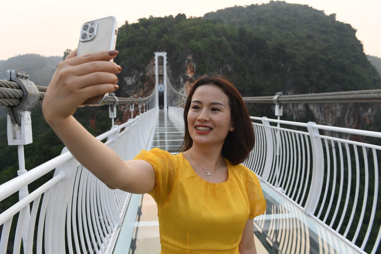 a woman takes a selfie on the Bach Long glass bridge in the Moc Chau district in Vietnam's Son La province