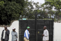 Plainclothes security forces and civilians stand outside the entrance to the Lhubiriha Secondary School following an attack on the school on Saturday, in Mpondwe, Uganda Sunday, June 18, 2023, near the border with Congo. Ugandan authorities have recovered the bodies of 41 people including 38 students who were burned, shot or hacked to death after suspected rebels attacked the school, according to the local mayor. (AP Photo/Hajarah Nalwadda)