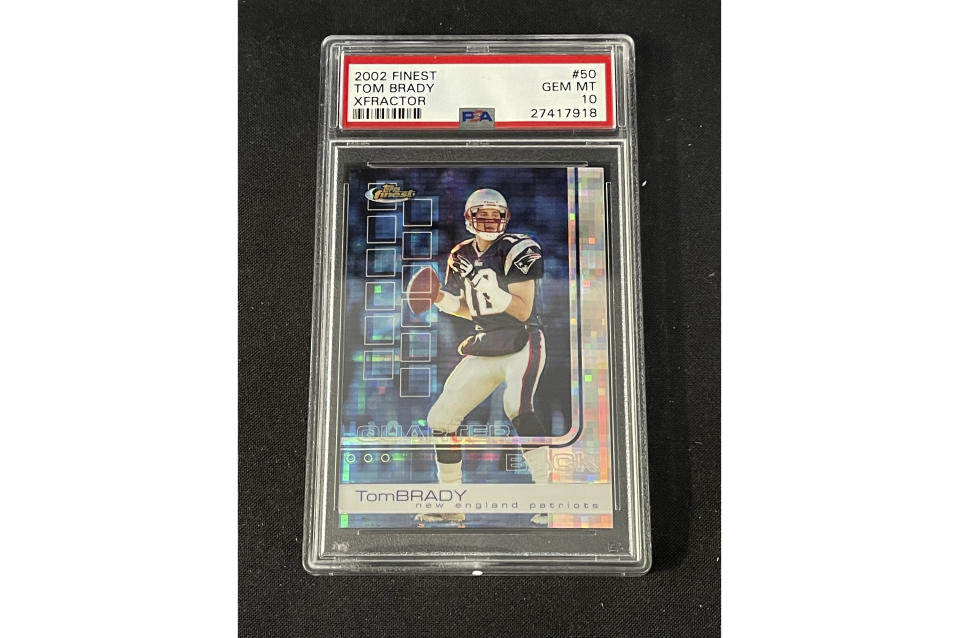 In this photo provided by Saco River Auction LLC, a 2002 Topps Finest X-Fractor card showing football quarterback Tom Brady rests inside a transparent case, Wednesday, Jan. 19, 2022, in Gorham, Maine. Troy Thibodeau from Saco River Auction estimates the card will fetch six figures when it's auctioned on Jan. 31. (Troy Thibodeau/Saco River Auction LLC via AP)