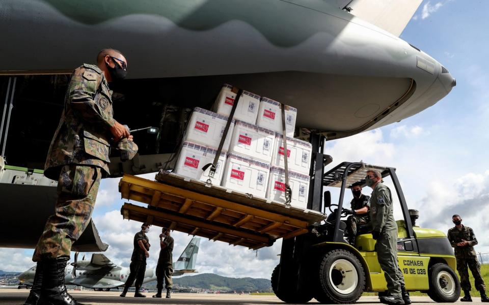 Members of the Brazilian army load 'Coronavac' vaccines, developed by the Chinese laboratory Sinovac, on a Brazilian Air Force aircraft. The Brazilian Ministry of Health yielded to the pressure of the governors and decided to start vaccine rollout two days earleir than planned - Sebastiao Moreira/EPA-EFE/Shutterstock