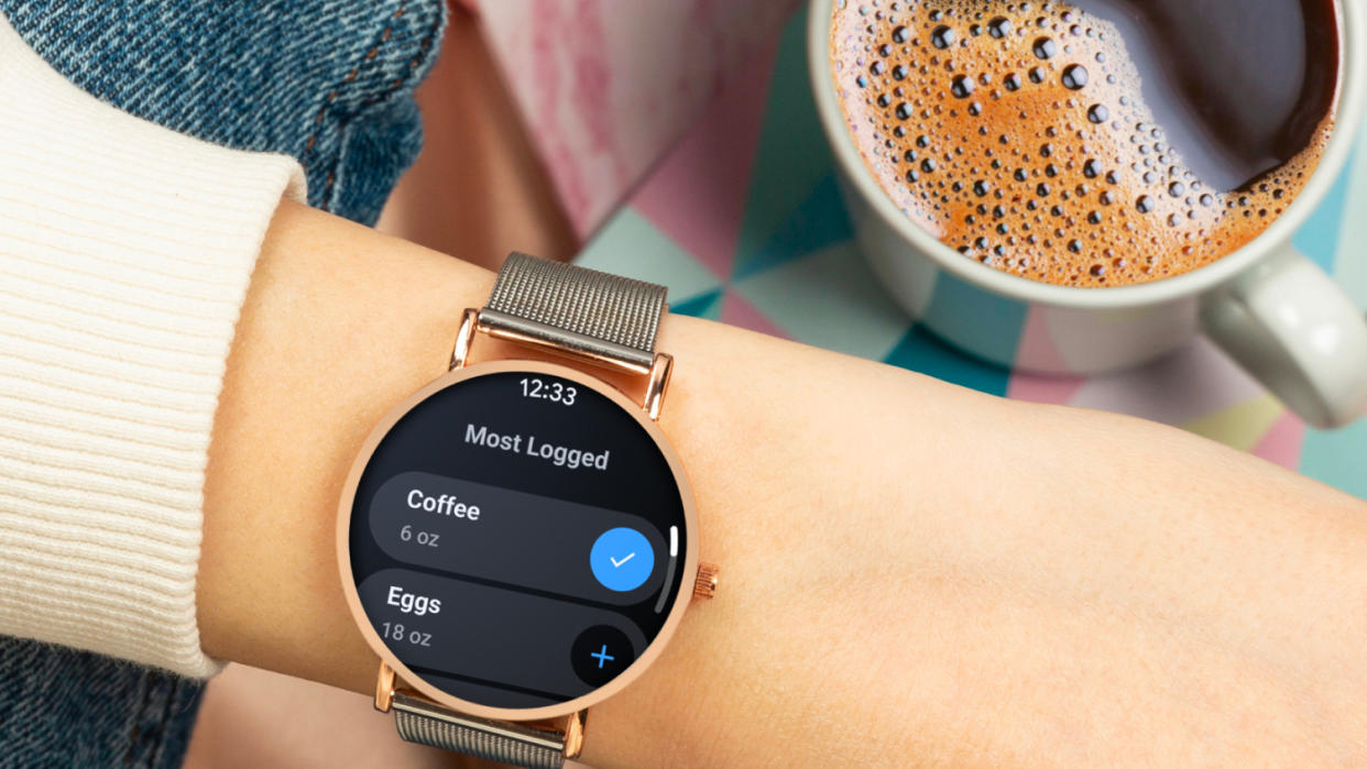  A Wear OS smartwatch on a wrist by a cup of coffee. 