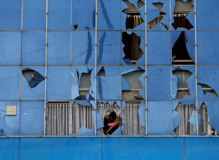 A man removes broken glass from a building after a suicide bomb attack in Kabul, Afghanistan November 16, 2017. REUTERS/Mohammad Ismail