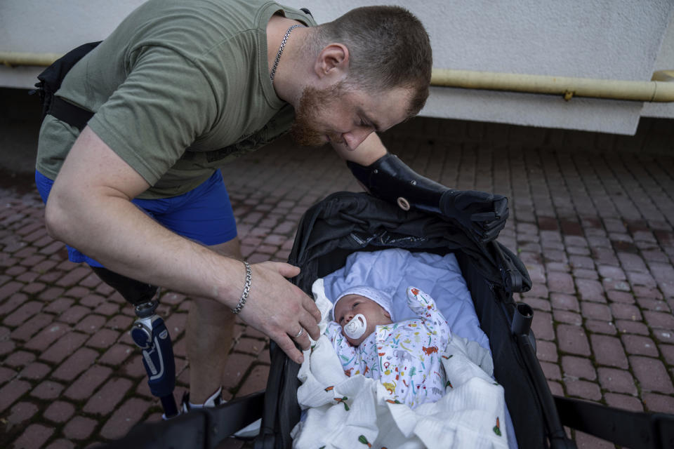 Mykhailo Yurchuk, a former Ukrainian paratrooper of the 95th brigade, speaks to his newborn daughter Olivia in Lviv, Ukraine, Wednesday, Aug. 23, 2023. In the 18 months since, Yurchuk has regained his equilibrium, both mentally and physically. He met the woman who would become his wife at the rehabilitation hospital, where she was a volunteer. (AP Photo/Evgeniy Maloletka)