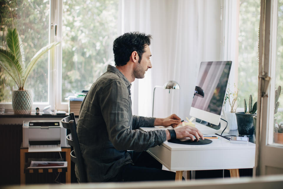 Side view of young businessman using computer while sitting at desk in home office