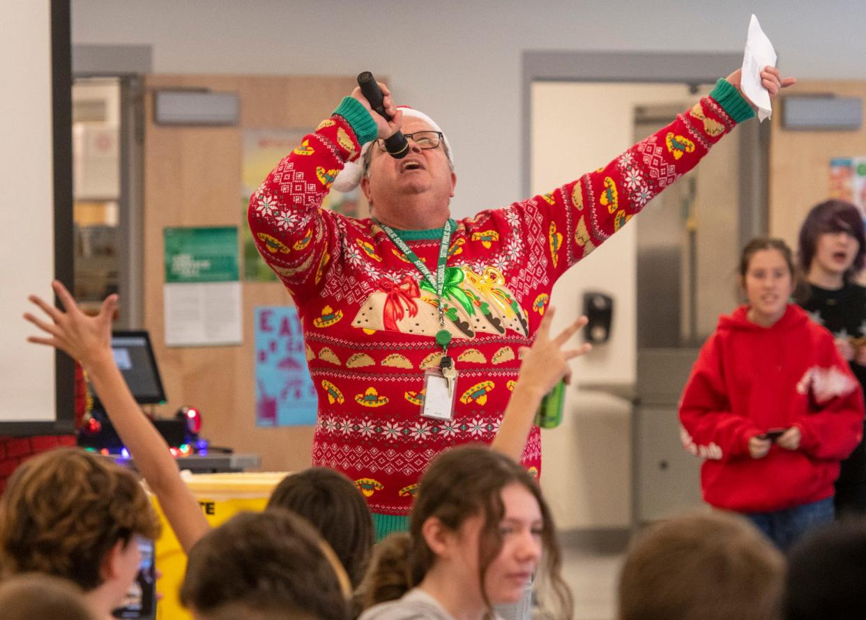 Seventh grade language teacher Michael Sharron sings "Rudolph the Red-Nosed Reindeer" with lyrics in Spanish, French, and English in the cafeteria filled with students at Sutton Middle School Thursday.