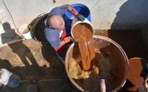 Saad Hussein, an Iraqi Yazidi, pours Arak into a large pot to produce Arak liquor out of dates, on the outskirts of Mosul