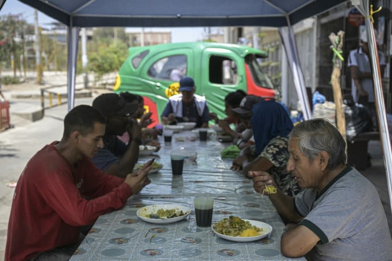 Personas almuerzan en un comedor local que ofrece platos hechos con cáscaras, tallos y otras partes nutritivas de los vegetales que suelen descartarse, en la periferia de Lima, el 5 de abril de 2024. (Ernesto BENAVIDES)