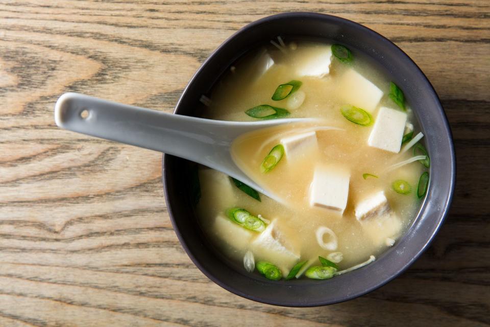 miso soup with tofu and scallions in a bowl with a spoon