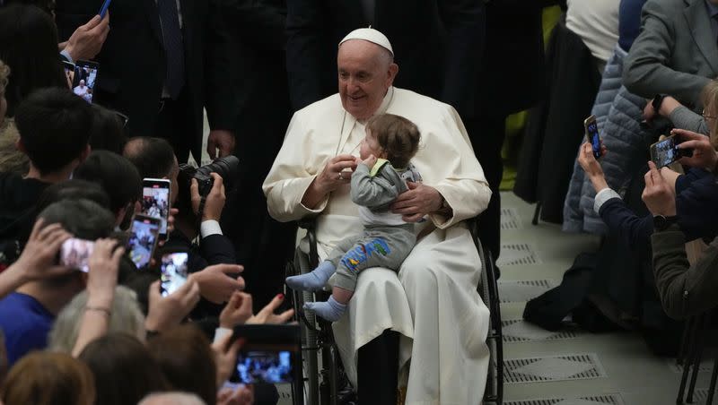 A child sits on Pope Francis’ lap after an audience with pilgrims from Rho diocese, in the Paul VI Hall, at the Vatican, Saturday, March 25, 2023. With a reformed sex abuse decree, Francis works to make adult victims heard.