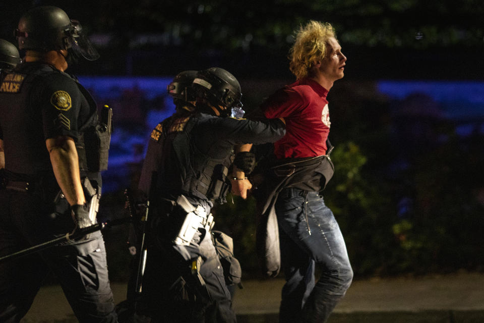 FILE - In this Aug. 30 2020 file photo police make arrests on the scene of protests at a Portland police precinct on in Portland, Ore. Amid protests following the police killing of George Floyd last year Portland dissolved a special police unit designed to focus on gun violence. Critics say the squad unfairly targeted Black people, but gun violence and homicides have since spiked in Oregon's largest city, and some say disbanding the 35-officer unit was a mistake. (AP Photo/Paula Bronstein,File)