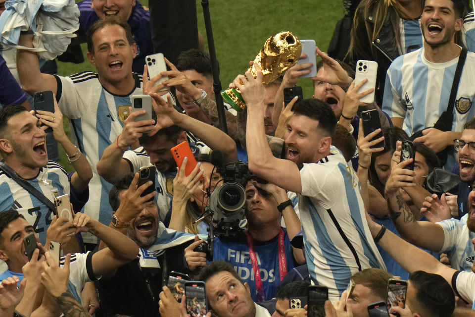 Argentina's Lionel Messi holds the winners trophy as he celebrates with fans after Argentina won the World Cup final soccer match against France at the Lusail Stadium in Lusail, Qatar, Sunday, Dec. 18, 2022. (AP Photo/Francisco Seco)