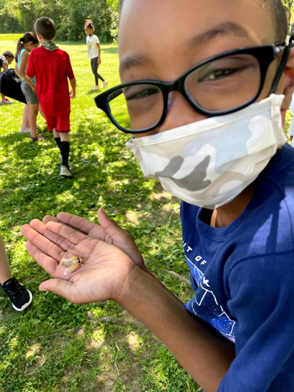 A student from teacher Nancy Murtaugh's fourth grade class in Fairfield, Ohio cups a newly molted periodical cicada in their hands in 2021.