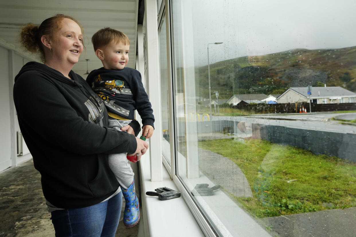 Becky Offland with her son Toby look out of the window of the Glan y Mor Hotel that she is renovating with her husband in Fairbourne village in Gwynedd in Wales, Wednesday, Oct. 20, 2021. (AP Photo/Kirsty Wigglesworth)