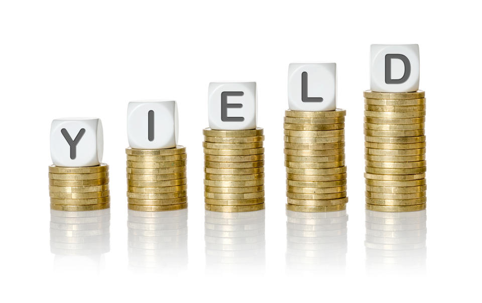 Dice spelling the word yield on top of stacks of gold coins