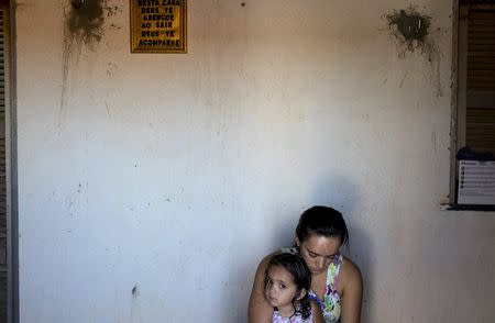 Marcia Xavier, daughter of late anti-pesticide activist Jose Maria Filho, who was shot 25 times with a 0.40 calibre pistol in April 2010 when driving home one night, sits with her mother outside their home in Limoeiro do Norte, in Ceara state, January 14, 2015. REUTERS/Davi Pinheiro TPX IMAGES OF THE DAY