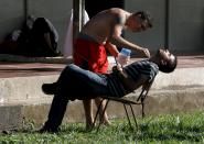 A Cuban migrant shaves a fellow migrant at a temporary shelter in a school in the town of La Cruz, Costa Rica, near the border with Nicaragua, November 17, 2015. More than a thousand Cuban migrants hoping to make it to the United States were stranded in the border town of Penas Blancas, Costa Rica, on Monday after Nicaragua closed its border on November 15, 2015 stoking diplomatic tensions over a growing wave of migrants making the journey north from the Caribbean island. REUTERS/Juan Carlos Ulate