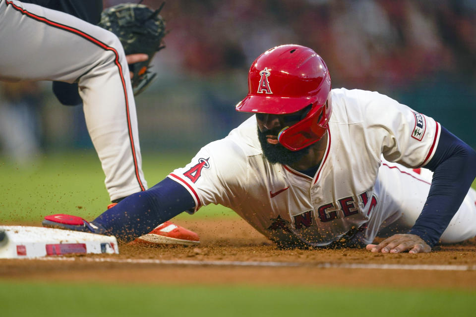 Los Angeles Angels' Jo Adell dives back to first after a pickoff attempt by Baltimore Orioles starting pitcher Grayson Rodriguez during the third inning of a baseball game, Tuesday, April 23, 2024, in Anaheim, Calif. (AP Photo/Ryan Sun)